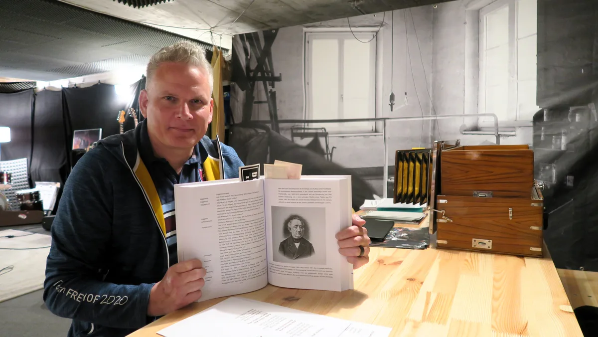 Man sieht einen Mann, der ein Buch hält.